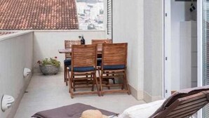 A balcony with a table and chairs, a lounge chair, and a view of a cityscape. - Apartment Adrian 2BR apartment with balcony (Dubrovnik)