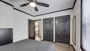 Un dormitorio con una cama, un ventilador de techo y una puerta que da a otra habitación.