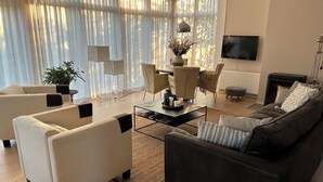A modern living room with a sofa, armchairs, a coffee table, and a TV.