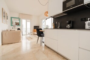 A modern kitchen with white cabinets, a Bosch microwave, and a coffee maker.