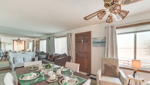 Un comedor con una mesa de madera dispuesta para cuatro, rodeada de sillas. Se observan un sofá y una silla al fondo.