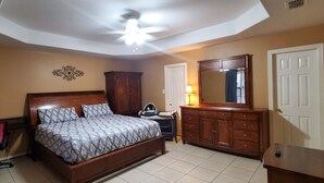 Une chambre à coucher comprenant un lit, un bureau, une chaise, une armoire et un ventilateur de plafond.