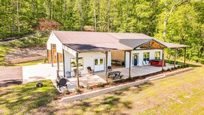 A two-story house with a covered porch, a barbecue area, and a patio with outdoor seating.