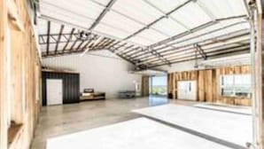 A spacious indoor area with a high ceiling and metal beams, featuring a large open space with a concrete floor and wooden paneling on the walls.