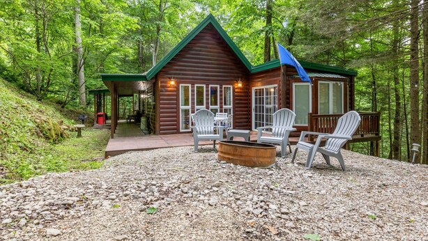 Een chalet met een veranda, buitenterras en een vuurkuil.