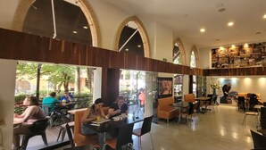 A spacious cafe with high ceilings, large windows, and a variety of seating arrangements. - EDIFICIO FENICIA (Medellín)