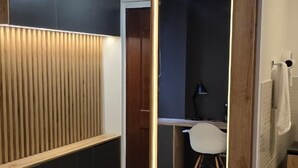 A modern bathroom with a wooden vanity, a mirror with LED lighting, and a dark-colored shower area. - EDIFICIO FENICIA (Medellín)