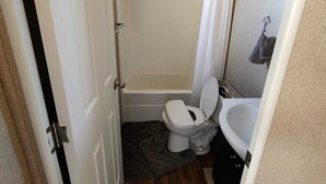A compact bathroom with a toilet, bidet, and bathtub.