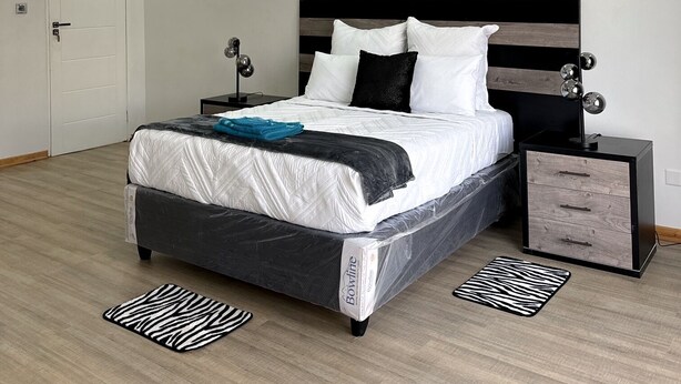Un dormitorio con cama, mesitas de noche, una lámpara en el techo y una puerta.