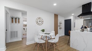 A modern kitchen with a marble countertop, a built-in stove, and a black range hood. - Chic and cozy home near the hospital: 3 comfy rooms, TVs, stylish amenities. (Gastonia)
