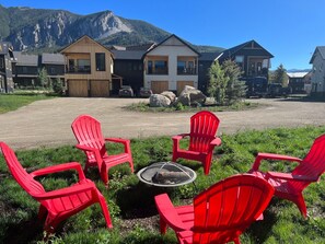 Relax in a serene outdoor seating area with a fire pit surrounded by Adirondack chairs.