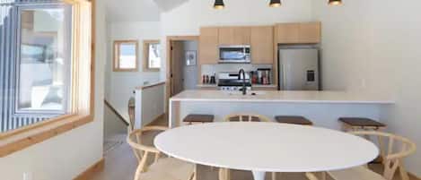 A modern kitchen with wooden cabinets, a central island, and pendant lighting.