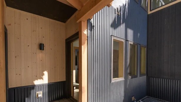 A wooden porch with a metal exterior wall and a door leading inside. - Modern Mountain Retreat, 360'Views,Minutes to Trails (Crested Butte)