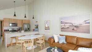 A modern kitchen with a central island, wooden chairs, a brown leather sofa, and a dining table. - Modern Mountain Retreat, 360'Views,Minutes to Trails (Crested Butte)