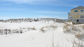 Une maison de plage avec un paysage sablonneux et un ciel dégagé.