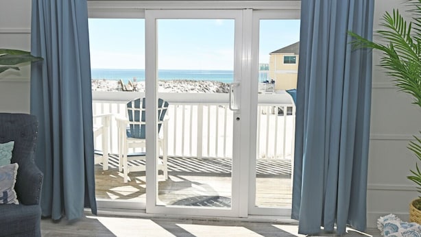 Une chambre avec vue sur la plage, accessible par une porte-fenêtre coulissante.
