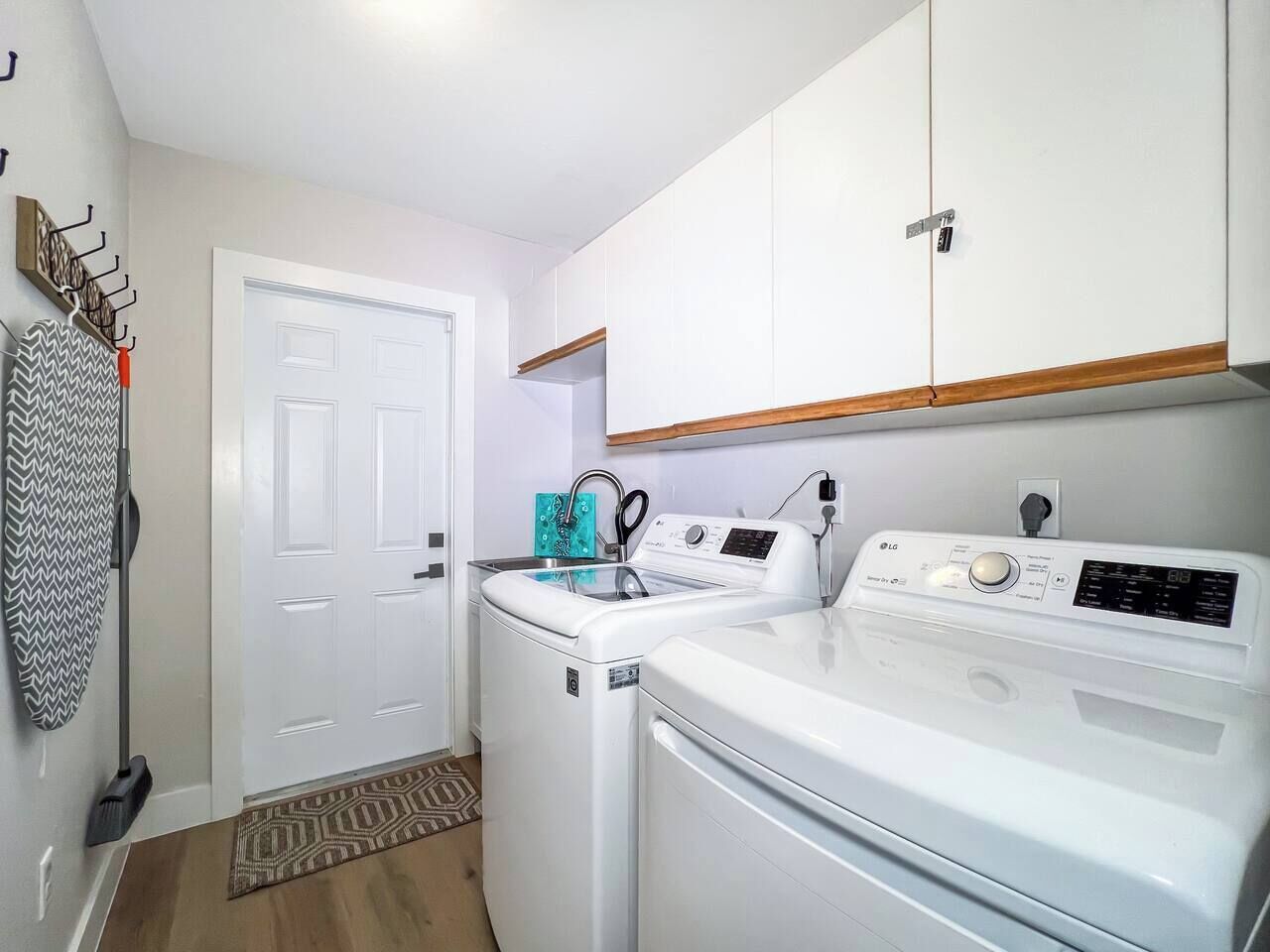 A compact laundry room with a washing machine, dryer, and ironing board.