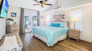 A bedroom with a bed, a ceiling fan, a TV, and a window with blinds. - Ruby's Retreat, heated pool, private oasis, fenced backyard (Cape Coral)
