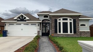 A two-story house with a garage, a stone facade, and a black front door. - Main House Listing 3BD/2BA

 (Edinburg)