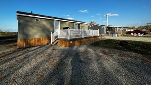 A row of mobile homes with a gravel driveway and a wooden fence. - Beautiful Cottage (508) in Vineyards of Niagara On The Lake (Niagara-on-the-Lake)