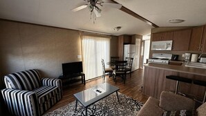 A compact living space with a sofa, a coffee table, a TV, a dining area, and a kitchenette. - Beautiful Cottage (508) in Vineyards of Niagara On The Lake (Niagara-on-the-Lake)