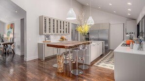 Una cucina moderna con isola centrale, sgabelli da bar e illuminazione a sospensione.