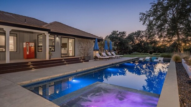 Una casa moderna con piscina, area relax all'aperto e una porta rossa.