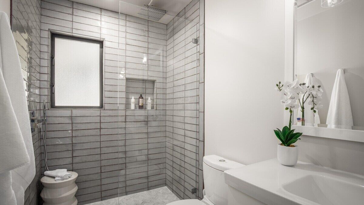 A modern bathroom with a shower, toilet, and sink.