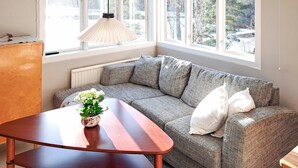 A cozy corner with a sofa, a wooden table, and a hanging light fixture.