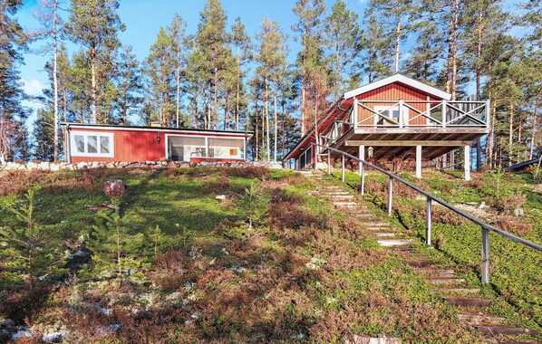 En hytte med rødt ydre, en overdækket veranda og en stensokkel.