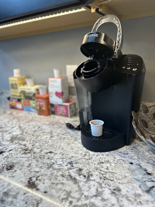 A coffee machine on a granite countertop with a coffee pod holder and a metal spoon.