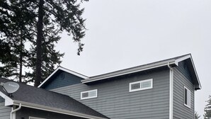 Une maison à deux étages avec un garage, un porche avant couvert et un mur d’accent en pierre.