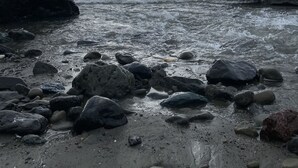 Une plage rocheuse, parsemée de gros rochers, où les vagues se brisent sur le rivage.