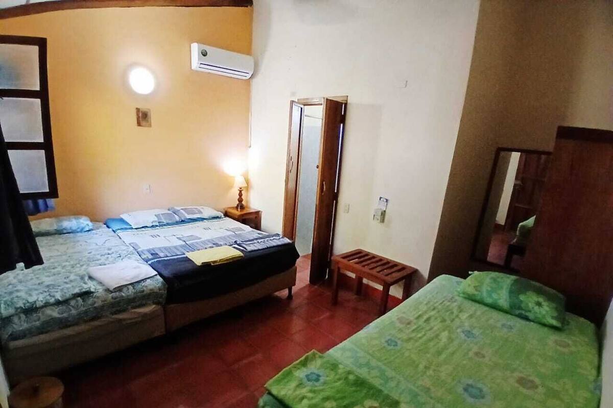 A room with two beds, a small wooden stool, a mirror, and a wall-mounted heater.