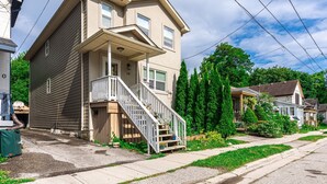 A two-story house with a front porch and a staircase leading to the entrance.