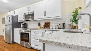 A modern kitchen with white cabinets, stainless steel appliances, and a granite countertop.
