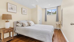 A bedroom with a bed, a nightstand, a lamp, and two framed pictures on the wall.