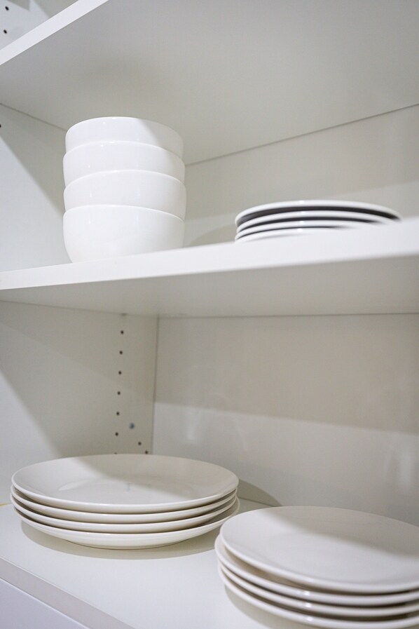 A white shelf with stacked white plates and bowls.