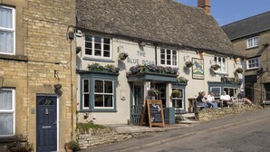 Un pub traditionnel appelé « The Blue Boar », avec une façade en pierre, de nombreuses fenêtres et des tables à l’extérieur.