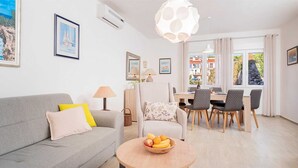 A modern living room with a grey sofa, a dining table with four chairs, and a large window with curtains. - Holiday house Sunshine in center of Jelsa (Jelsa)