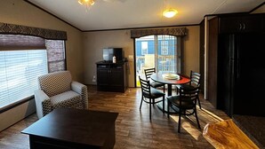 A compact living space with a dining area, a sofa, a TV, and a ceiling fan. - Beautiful Cottage (230) in Vineyards of Niagara On The Lake (Niagara-on-the-Lake)