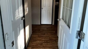 A hallway with wooden flooring, white doors, and a ceiling light. - Beautiful Cottage (230) in Vineyards of Niagara On The Lake (Niagara-on-the-Lake)