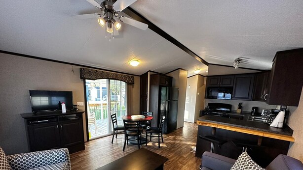 A compact living space with a kitchenette, a dining area, and a seating area with patterned sofas and a coffee table. - Beautiful Cottage (230) in Vineyards of Niagara On The Lake (Niagara-on-the-Lake)