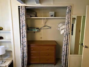 Una habitación con un aparador de madera, un perchero y una estantería con una caja y una bolsa.