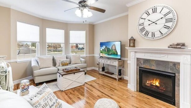 Ein Wohnzimmer mit Kamin, einer großen Wanduhr und einem Fernseher.