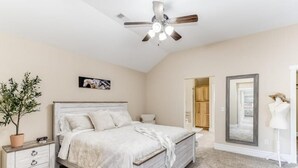 Ein Schlafzimmer mit Bett, Kommode, Deckenventilator, Blumentopf und Spiegel.