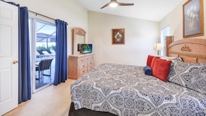 Une chambre à coucher comprenant un lit, une commode, un téléviseur et un ventilateur de plafond.