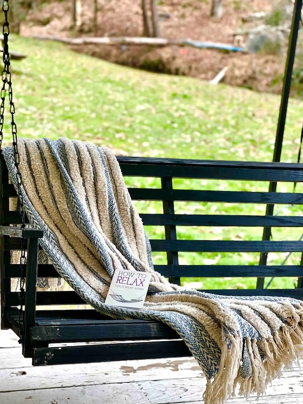 Un banco de madera negra con un plaid beige y azul.