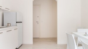 Una cucina moderna con mobili bianchi, un frigorifero bianco e un tavolo da pranzo con sedie.