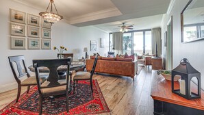 Ein geräumiges Wohnzimmer mit Holzboden, einem braunen Sofa, einem Esstisch mit Stühlen und einer Pendelleuchte.